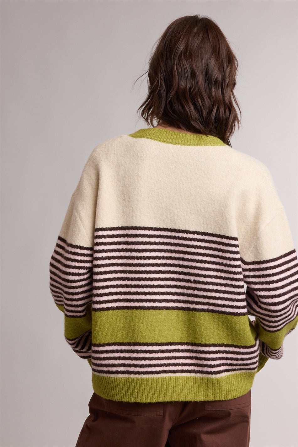 A women's relaxed crewneck knit cardigan featuring wide avocado green colorblocking and horizontal espresso stripes on a cream background with tortoiseshell-look front buttons.