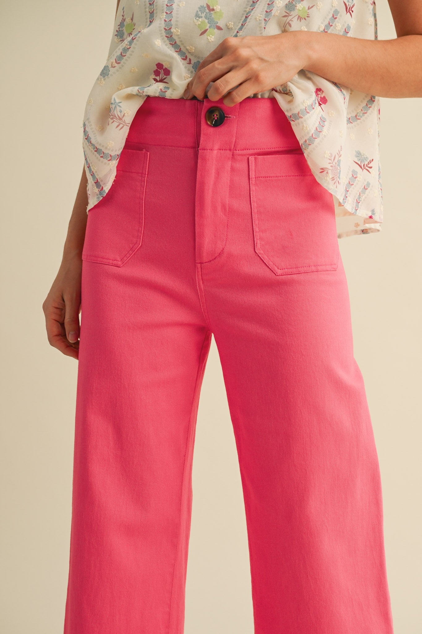 A pair of women's high-waisted wide-leg cropped cotton twill pants in a vibrant berry pink color featuring classic front patch pockets and a button zip closure.