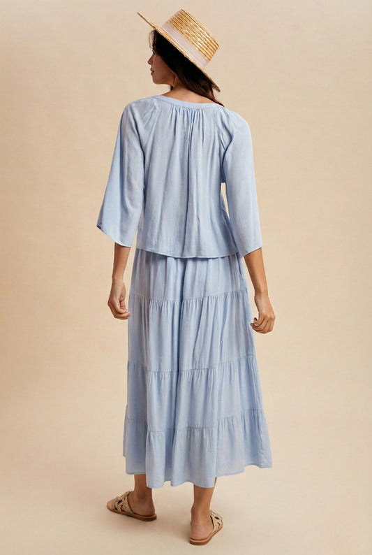A two-piece sky blue set featuring a tie-front blouse with delicate lace trim details and short flowy sleeves paired with a matching tiered midi skirt.