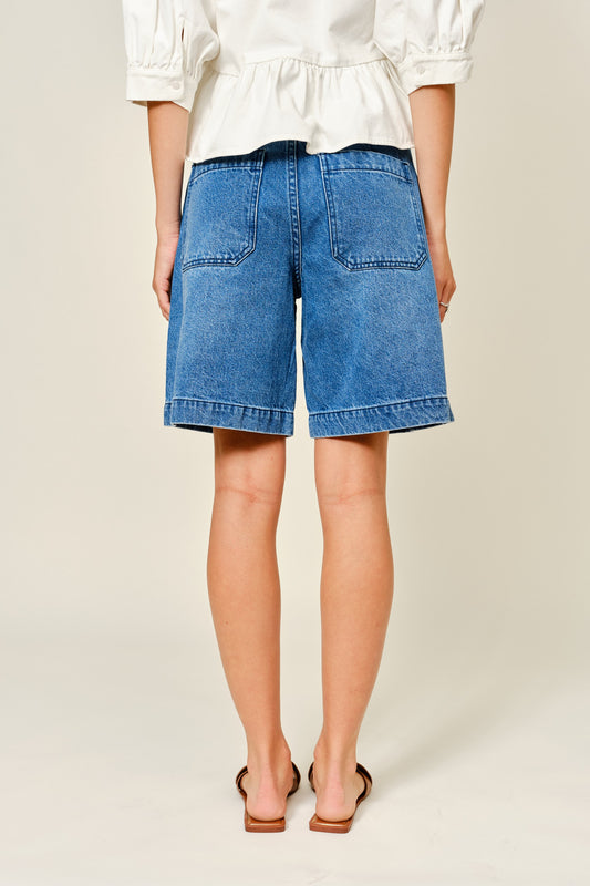 Medium Wash denim bermuda shorts. Large front pockets. Button and zipper closure. Back pockets.