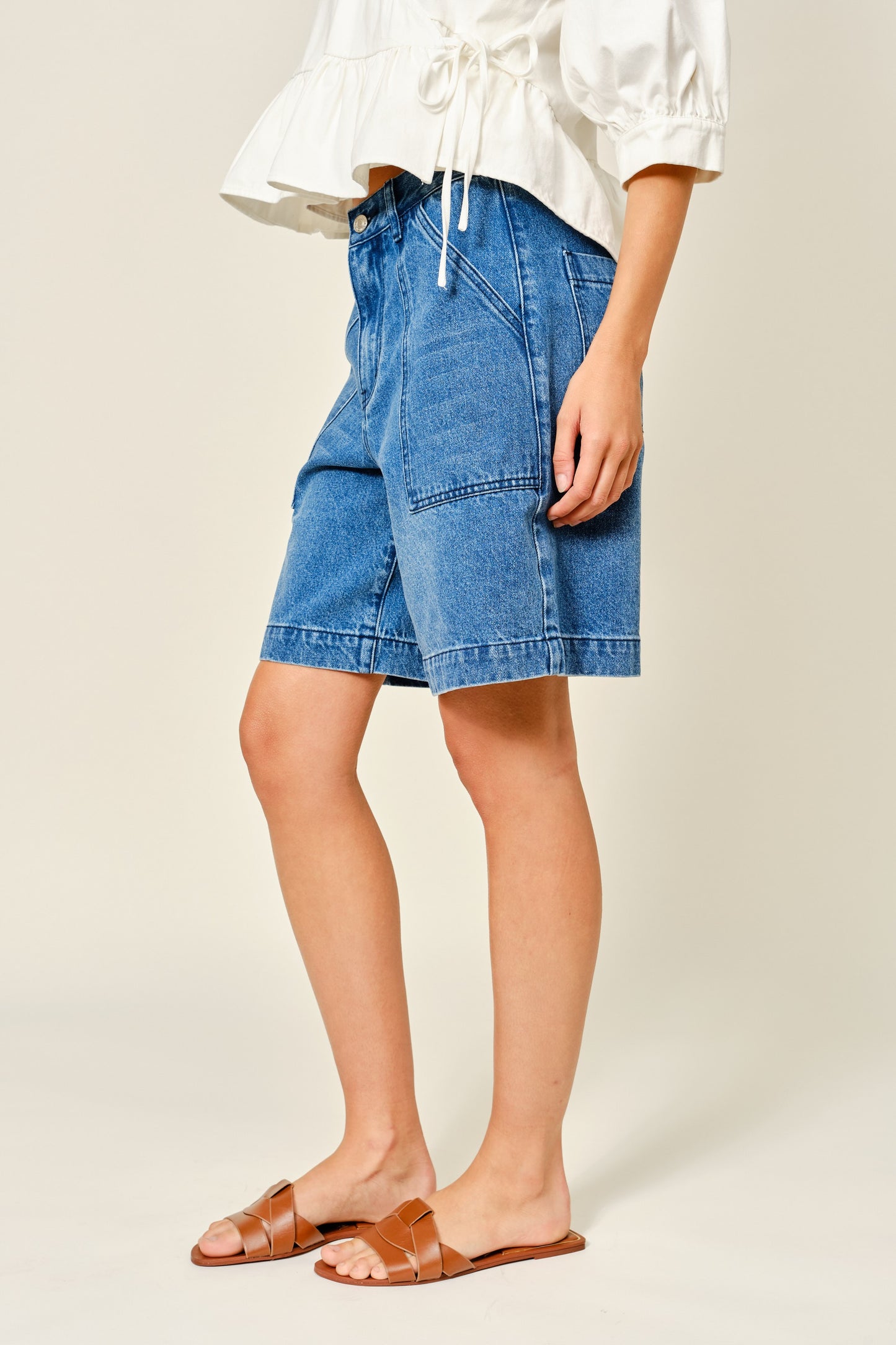 Medium Wash denim bermuda shorts. Large front pockets. Button and zipper closure. Back pockets.