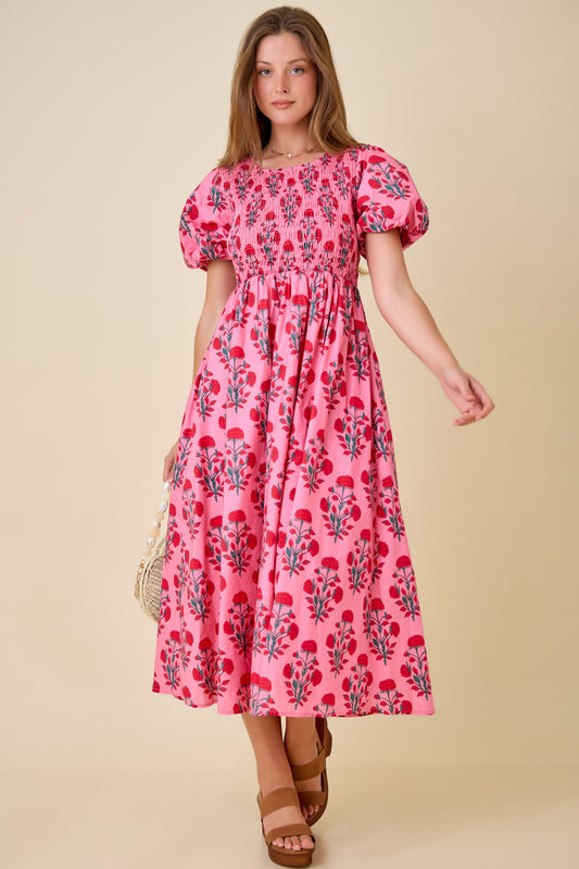 A short-sleeve fuchsia and red floral midi dress featuring a fully smocked bodice, a square neckline, and voluminous puff sleeves with elastic cuffs.