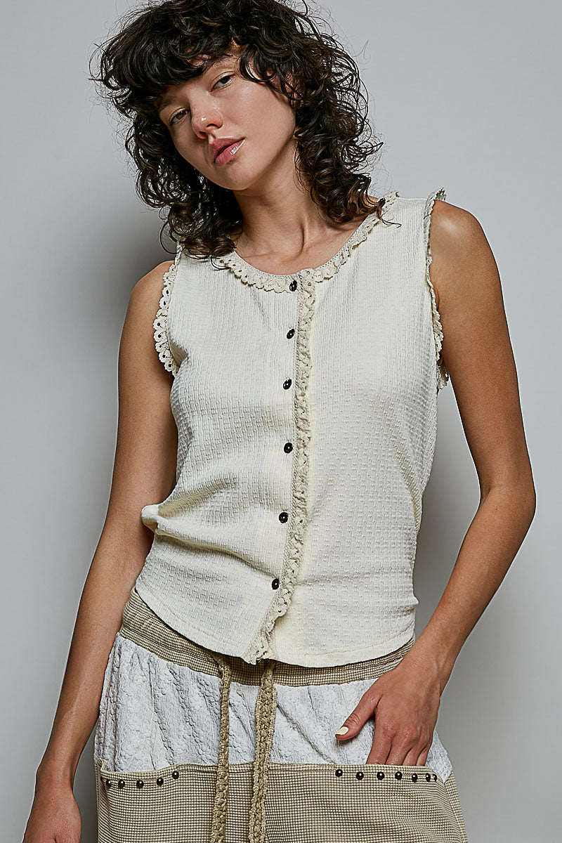 A women's sleeveless cream textured waffle-knit top featuring a button-front closure and delicate eyelet lace trimming along the round neckline and armholes.