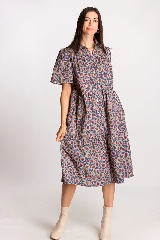 A navy and mauve floral print midi dress featuring a full button-up front, a structured collar, and short puff sleeves with a tiered skirt.
