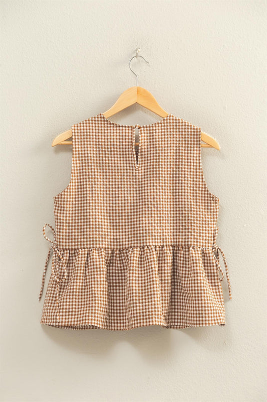 Textured brown gingham sleeveless top with a round neck, peplum skirt, bow details on the side, and keyhole in the back.