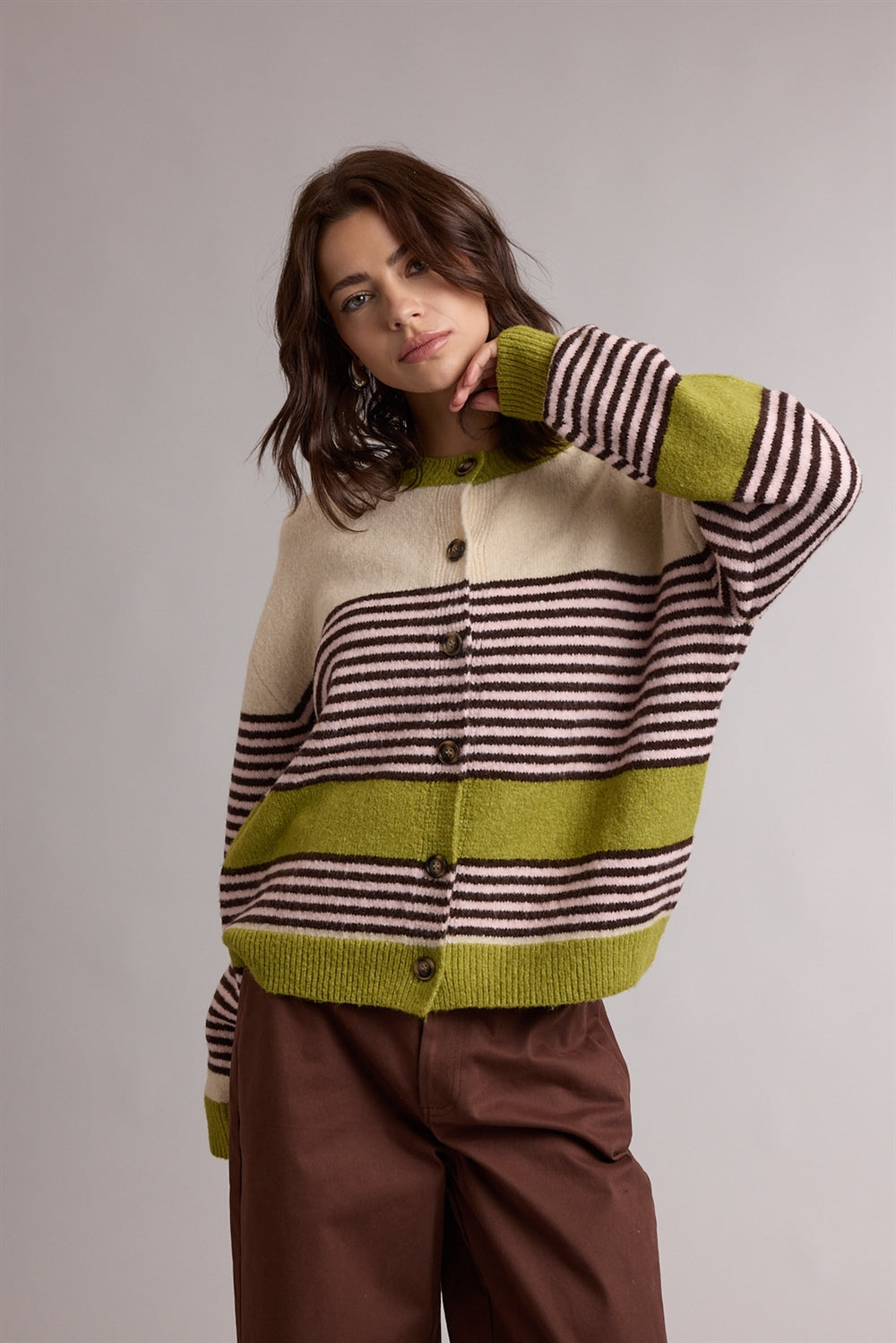 A women's relaxed crewneck knit cardigan featuring wide avocado green colorblocking and horizontal espresso stripes on a cream background with tortoiseshell-look front buttons.