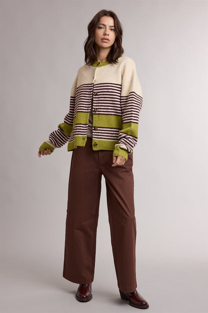 A women's relaxed crewneck knit cardigan featuring wide avocado green colorblocking and horizontal espresso stripes on a cream background with tortoiseshell-look front buttons.