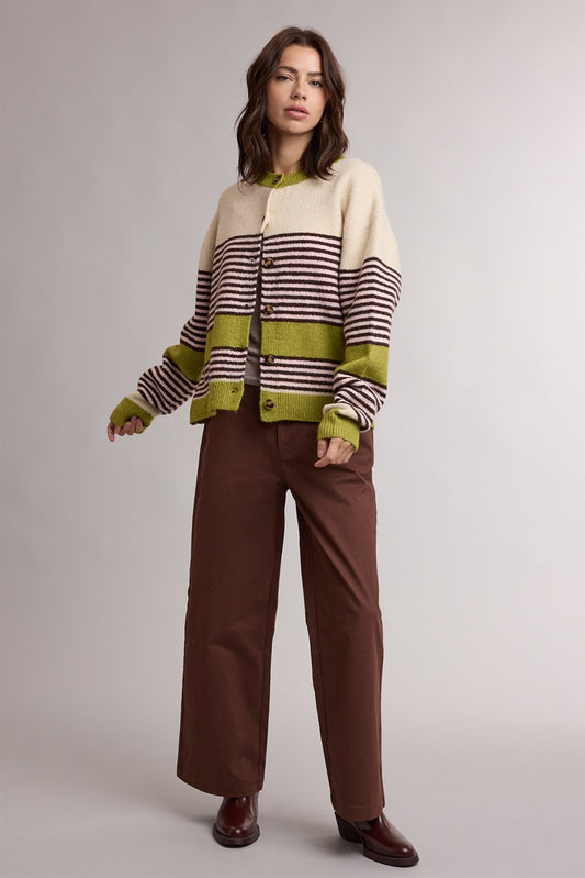 A women's relaxed crewneck knit cardigan featuring wide avocado green colorblocking and horizontal espresso stripes on a cream background with tortoiseshell-look front buttons.