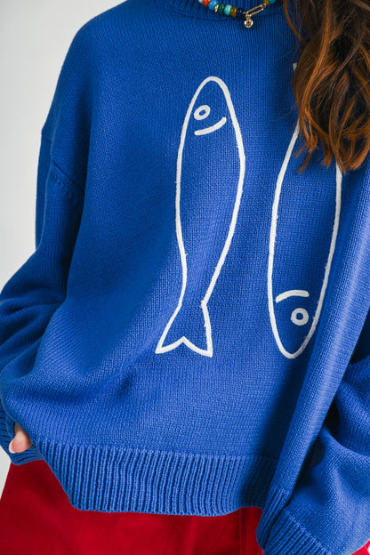 A women's royal blue long-sleeve knit crewneck sweater featuring a white embroidered sardine graphic on the front and ribbed trim along the collar, cuffs, and hem.