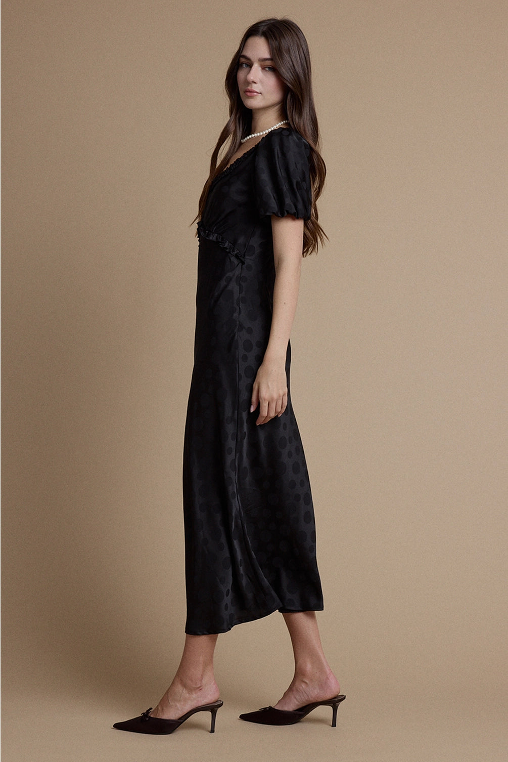 A women's black satin jacquard polka dot midi dress featuring short puff sleeves, a scoop neckline with ruffle trim, and a high empire waistline.