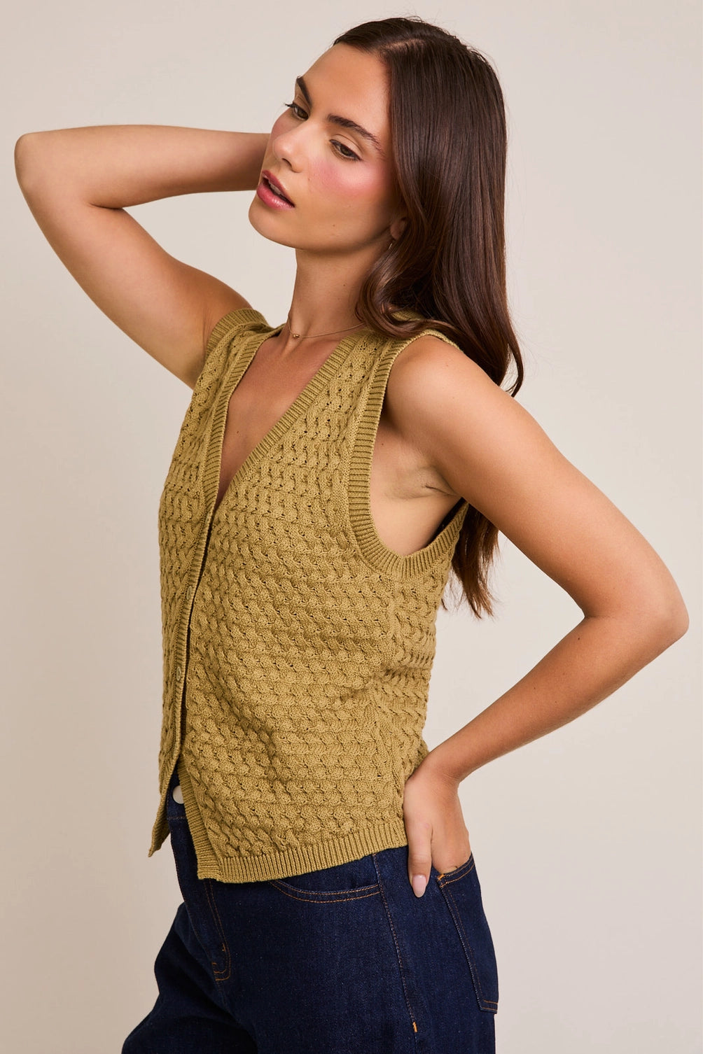 A women's sleeveless olive green button-front vest knit top featuring an intricate textured basketweave pattern, a modest V-neckline, and ribbed trim along the split hem.