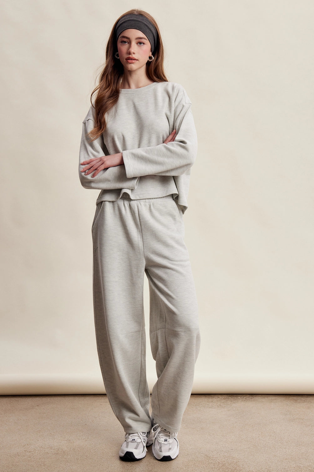 A women's heather gray two-piece stretch cotton lounge set featuring a long-sleeve crewneck top and matching high-waisted relaxed wide-leg pants.