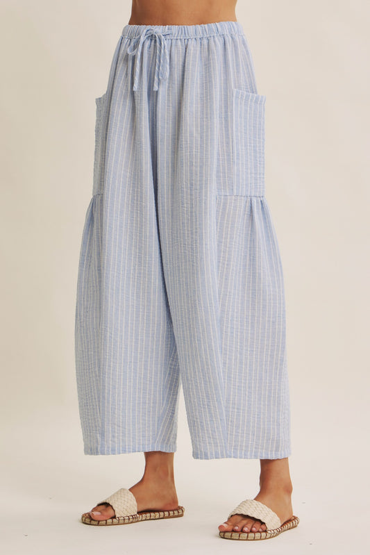 Striped Pants offer a relaxed fit, an elastic waistband with adjustable drawstring with voluminous legs and dropped side pockets in light blue. 