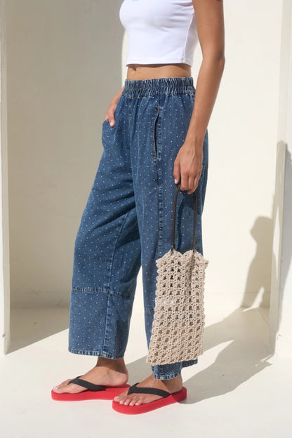 High-waisted wide-leg denim pants featuring an all-over white micro polka dot print, a comfortable smocked elastic waistband, and functional side pockets.