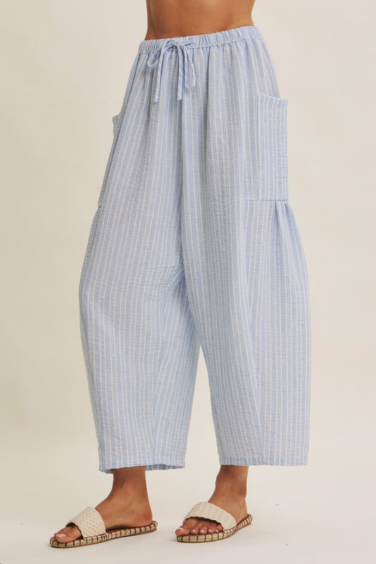 Striped Pants offer a relaxed fit, an elastic waistband with adjustable drawstring with voluminous legs and dropped side pockets in light blue. 