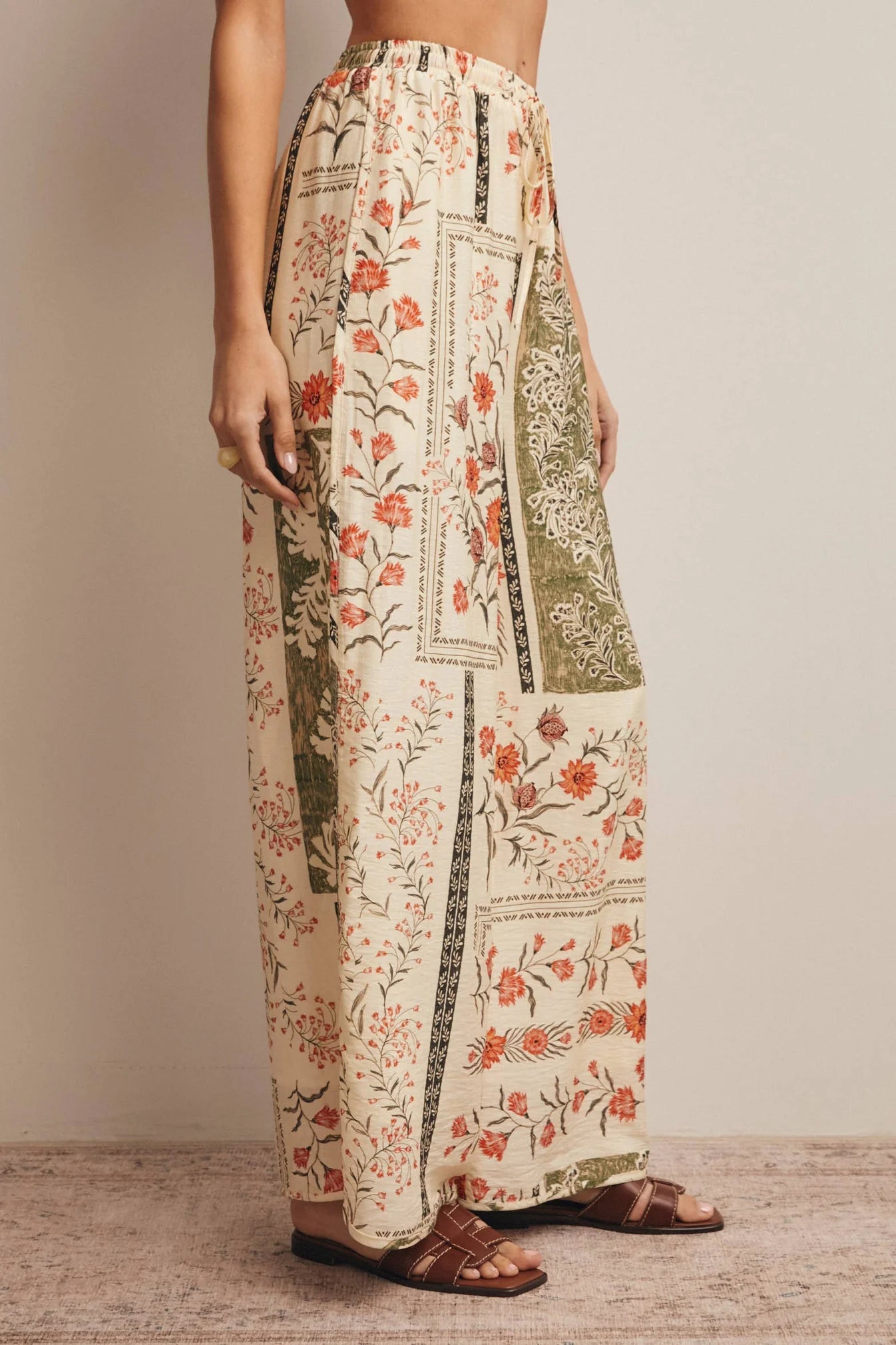 High-waisted wide-leg patchwork floral print pants in ecru, terracotta, and olive green featuring a comfortable elastic drawstring waistband and a relaxed silhouette.