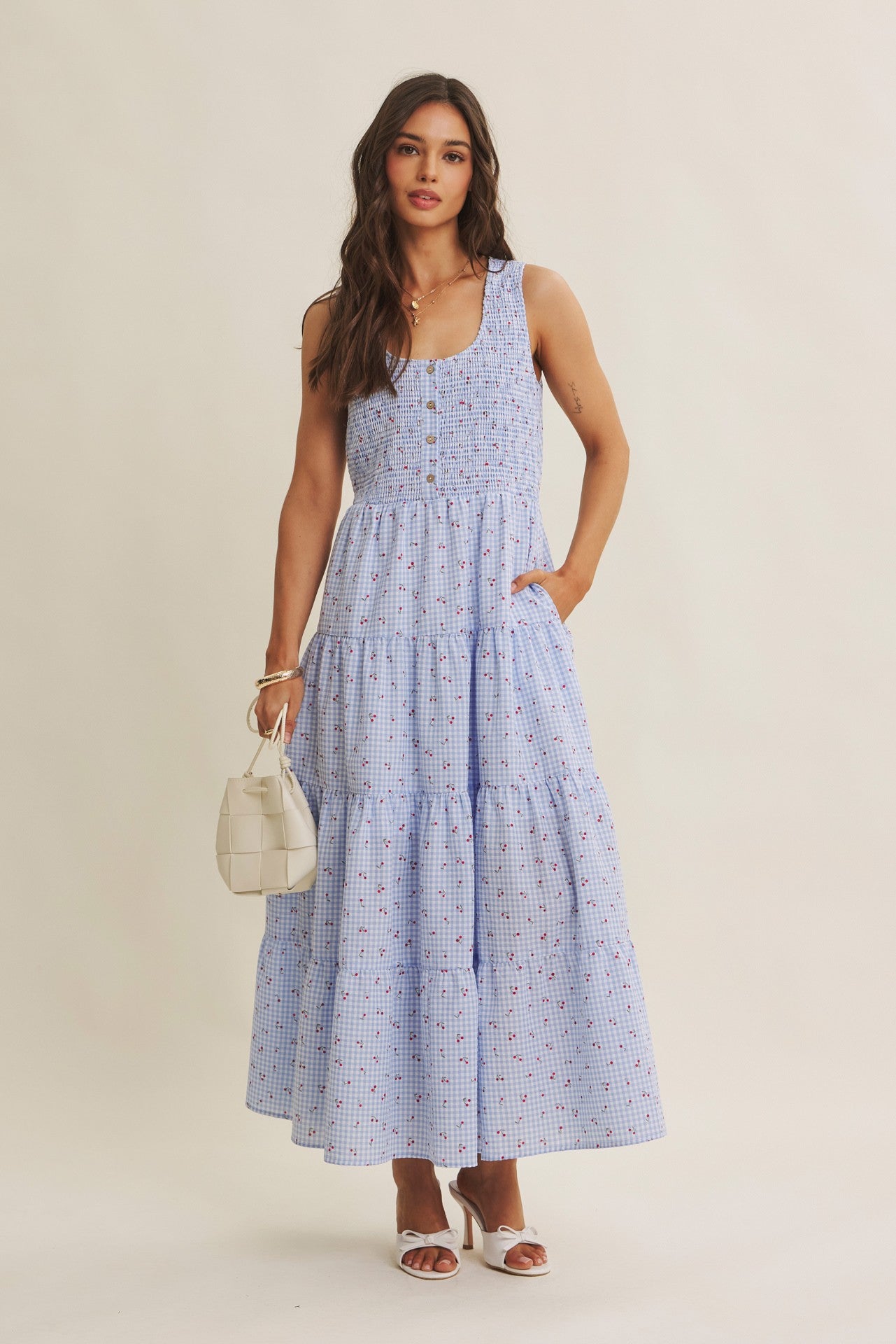 Cherry gingham print maxi dress in the color sky blue. The dress has a smocked bust, round neck, button-down detail, side pockets and comes lined. 
