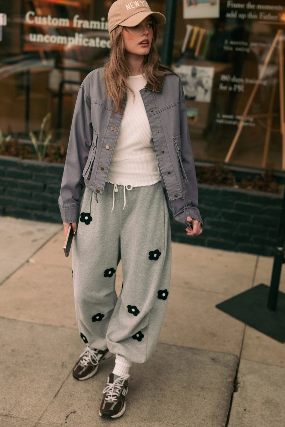 A women's heather gray wide-leg fleece sweatpants featuring an elastic drawstring waistband, relaxed barrel leg, and black chenille flower patches across the front and back.