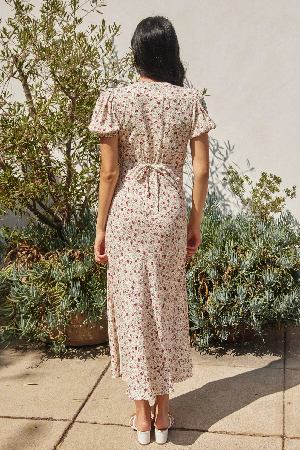 A women's short puff sleeve maxi dress in cream featuring a ditsy rose pink floral print, a modest surplice V-neckline, and a flowing skirt.