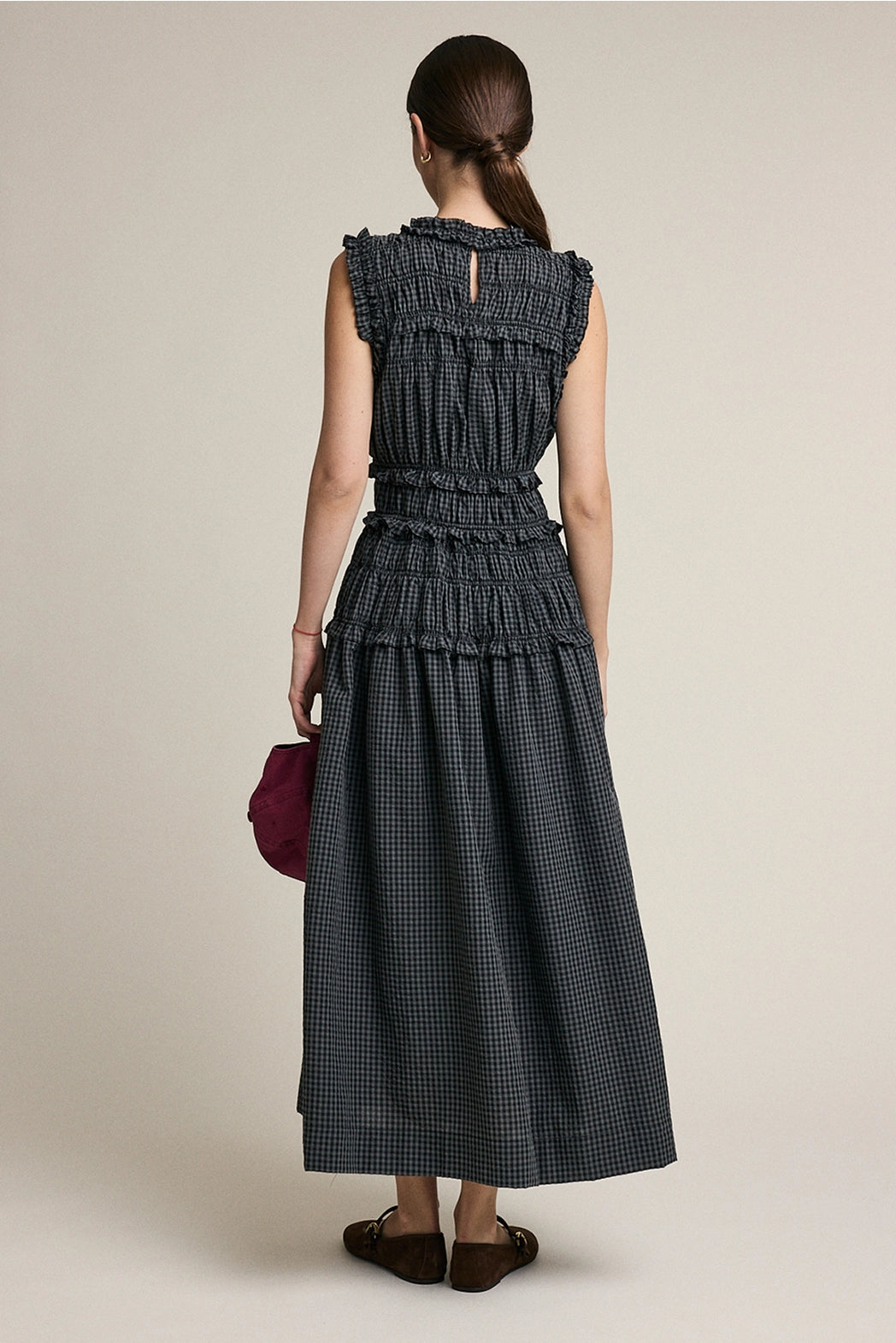 A women's sleeveless maxi dress in a dark gray and black plaid pattern featuring a high ruffled neckline, a fully elasticized smocked bodice, and a flowing tiered skirt with delicate ruffle trim.