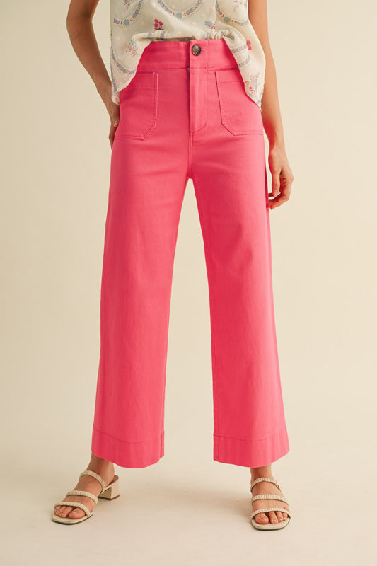 A pair of women's high-waisted wide-leg cropped cotton twill pants in a vibrant berry pink color featuring classic front patch pockets and a button zip closure.