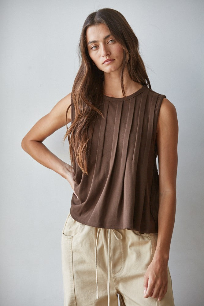 A sleeveless chocolate brown knit top featuring structured vertical front pleats, a classic crew neckline, and a relaxed silhouette.