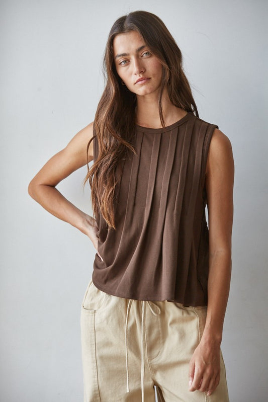 A sleeveless chocolate brown knit top featuring structured vertical front pleats, a classic crew neckline, and a relaxed silhouette.