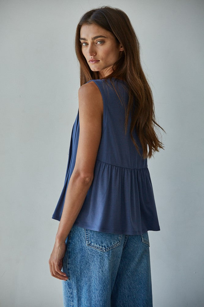A sleeveless midnight blue knit top featuring structured vertical front pleats, a classic crew neckline, and a relaxed silhouette.