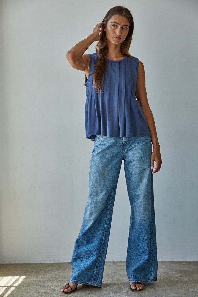 A sleeveless midnight blue knit top featuring structured vertical front pleats, a classic crew neckline, and a relaxed silhouette.