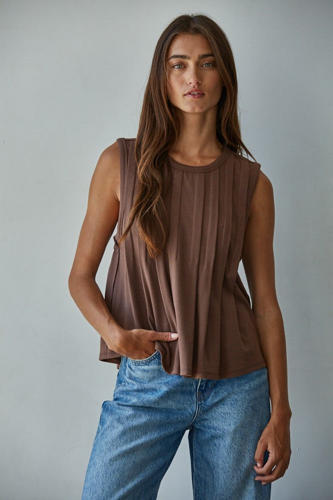 A sleeveless chocolate brown knit top featuring structured vertical front pleats, a classic crew neckline, and a relaxed silhouette.
