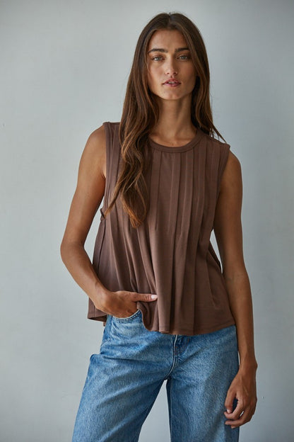 A sleeveless chocolate brown knit top featuring structured vertical front pleats, a classic crew neckline, and a relaxed silhouette.