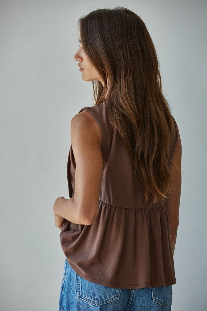 A sleeveless chocolate brown knit top featuring structured vertical front pleats, a classic crew neckline, and a relaxed silhouette.