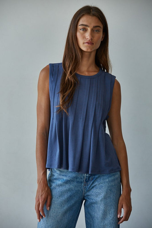 A sleeveless midnight blue knit top featuring structured vertical front pleats, a classic crew neckline, and a relaxed silhouette.