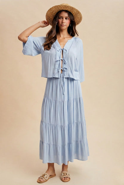 A two-piece sky blue set featuring a tie-front blouse with delicate lace trim details and short flowy sleeves paired with a matching tiered midi skirt.