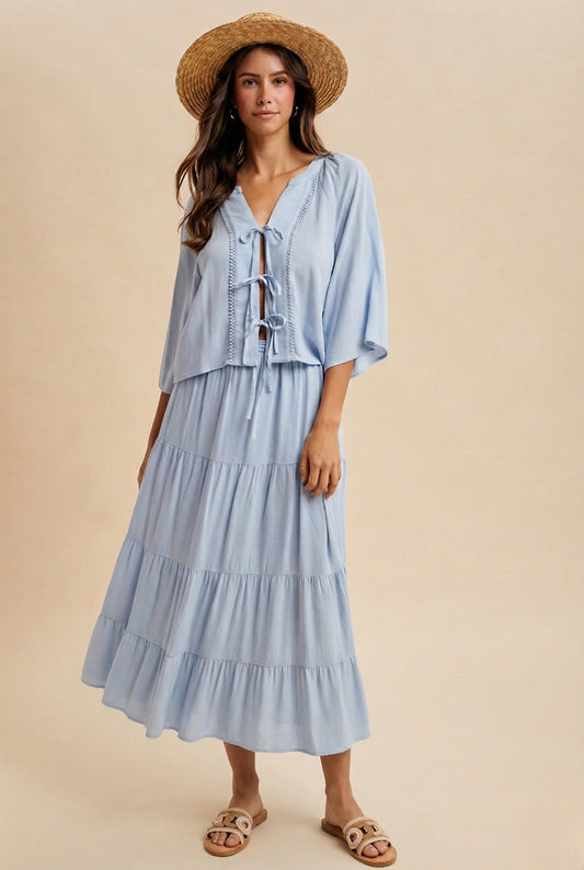 A two-piece sky blue set featuring a tie-front blouse with delicate lace trim details and short flowy sleeves paired with a matching tiered midi skirt.