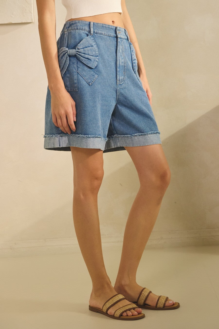 Bow Pocket Short in Washed Denim. Cuffed hem, button and zipper closure, smocking on the back, and a 6.5" inseam. 