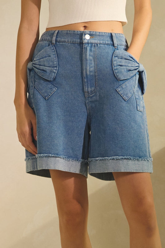 Bow Pocket Short in Washed Denim. Cuffed hem, button and zipper closure, smocking on the back, and a 6.5" inseam. 