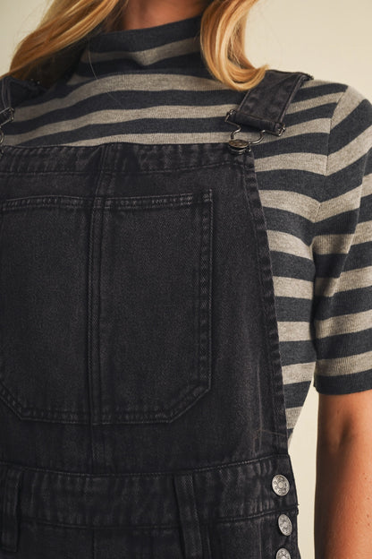 A pair of women's high-waisted wide-leg twill overalls in a vintage washed black denim finish featuring classic adjustable shoulder straps, a front chest pocket, and side pockets.