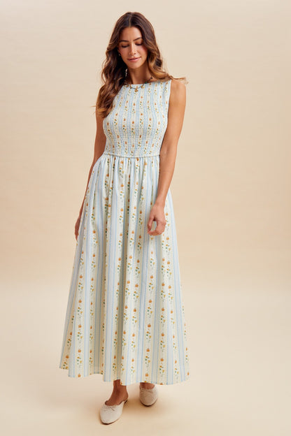 A sleeveless women's high-neck midi dress featuring a fully smocked bodice, convenient side pockets, and an A-line skirt with a vertical blue and orange floral stripe pattern.