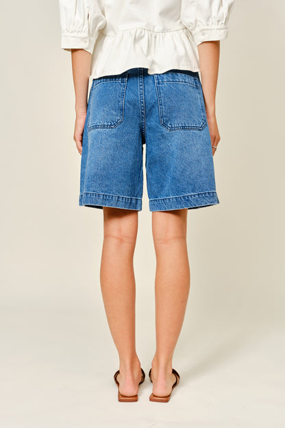 Medium Wash denim bermuda shorts. Large front pockets. Button and zipper closure. Back pockets. 