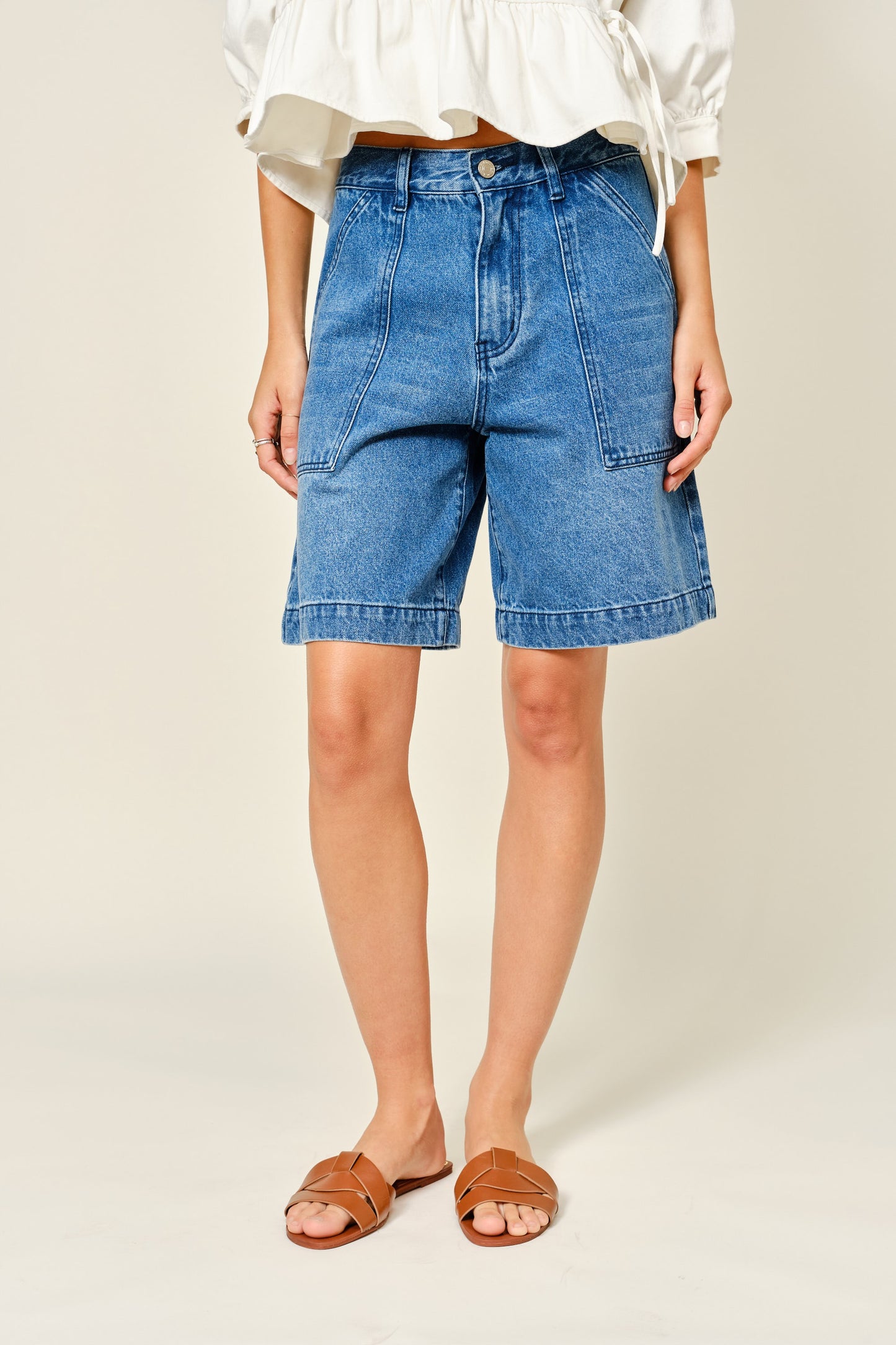 Medium Wash denim bermuda shorts. Large front pockets. Button and zipper closure. 
