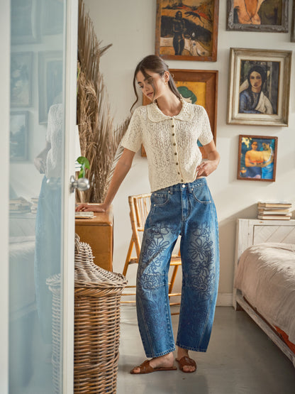 A pair of high-waisted women's barrel jeans in a dark wash featuring intricate tonal blue floral embroidery down the front of the curved legs.