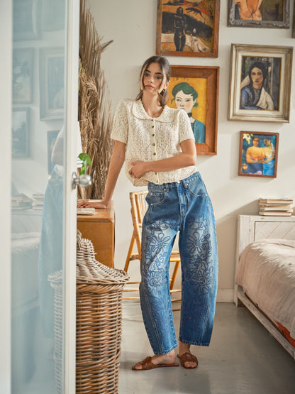 A pair of high-waisted women's barrel jeans in a dark wash featuring intricate tonal blue floral embroidery down the front of the curved legs.