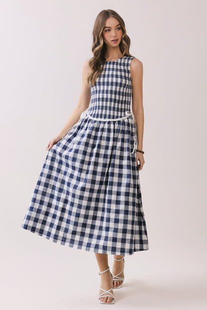 Sleeveless navy and white gingham dress with a smocked bodice and a waist tie detail. 