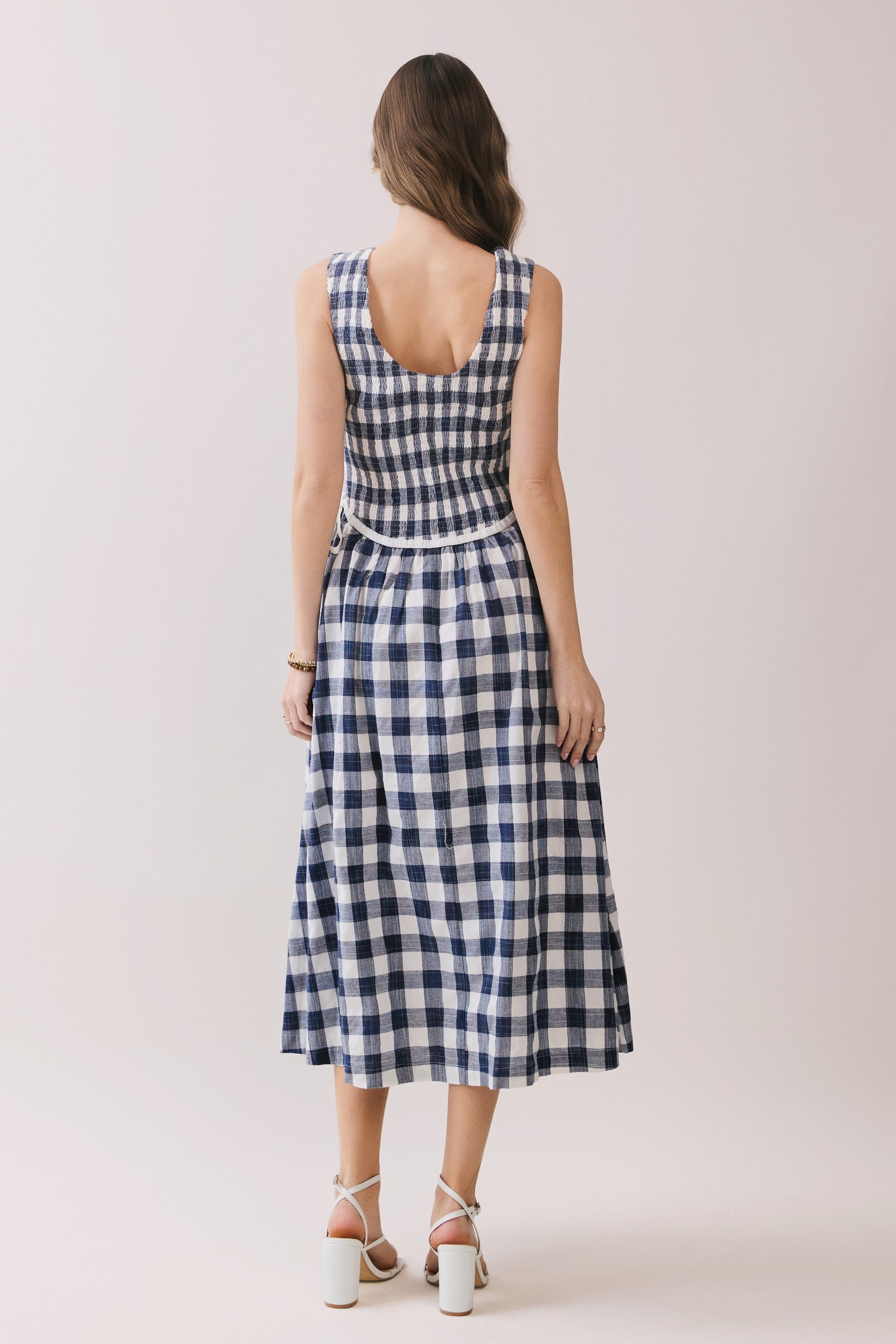 Sleeveless navy and white gingham dress with a smocked bodice and a waist tie detail. 
