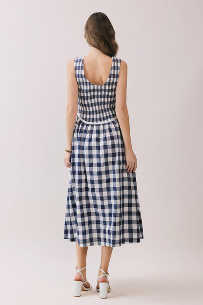Sleeveless navy and white gingham dress with a smocked bodice and a waist tie detail. 