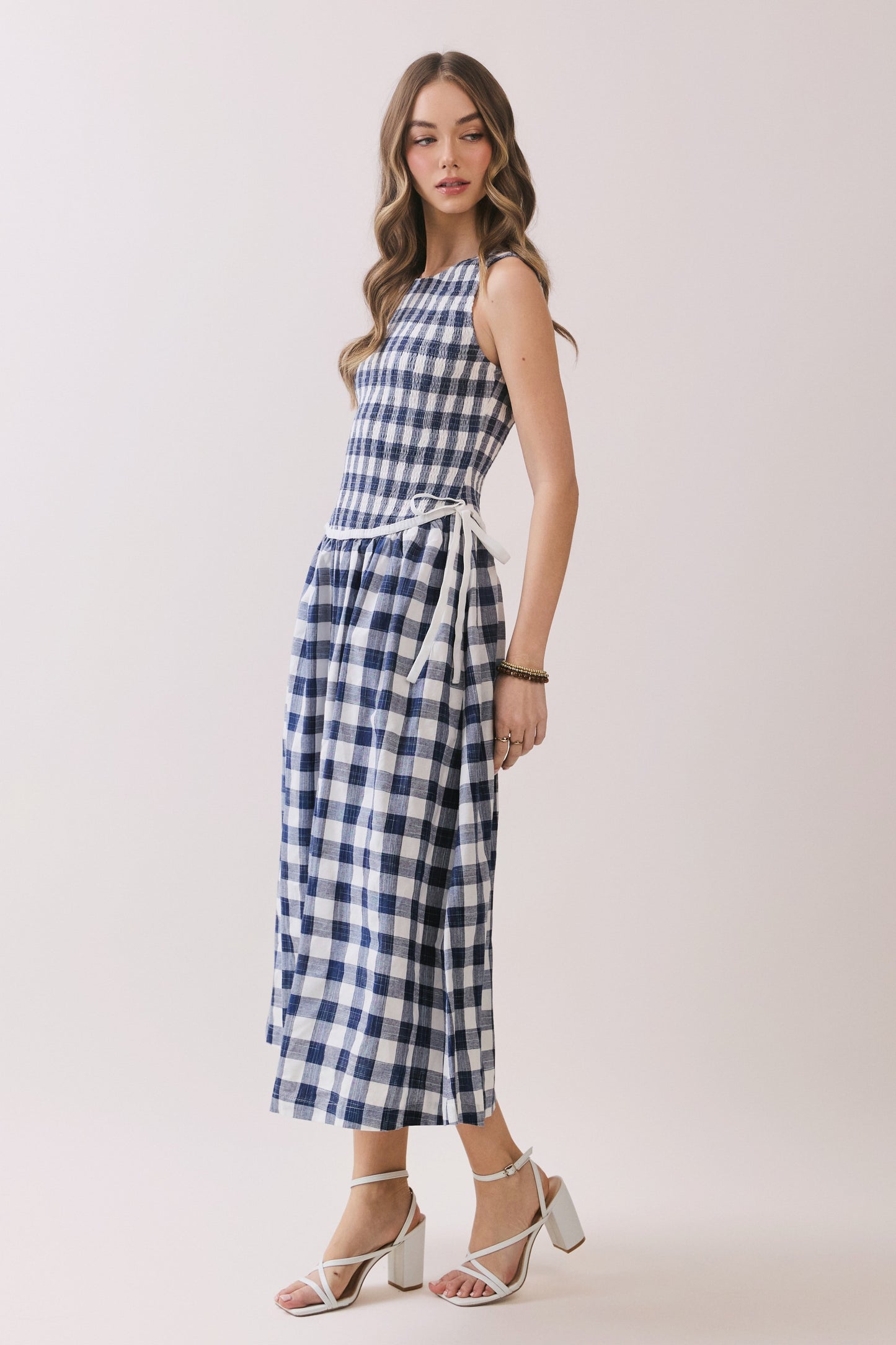 Sleeveless navy and white gingham dress with a smocked bodice and a waist tie detail. 