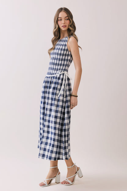 Sleeveless navy and white gingham dress with a smocked bodice and a waist tie detail. 