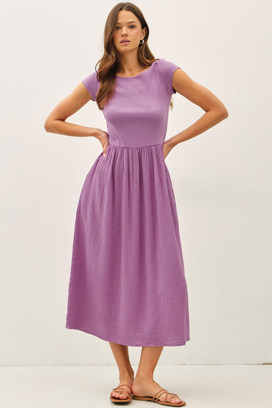 iris purple midi dress featuring a wide boat neckline, short cap sleeves, and a soft gathered waistline with a relaxed flowy skirt.
