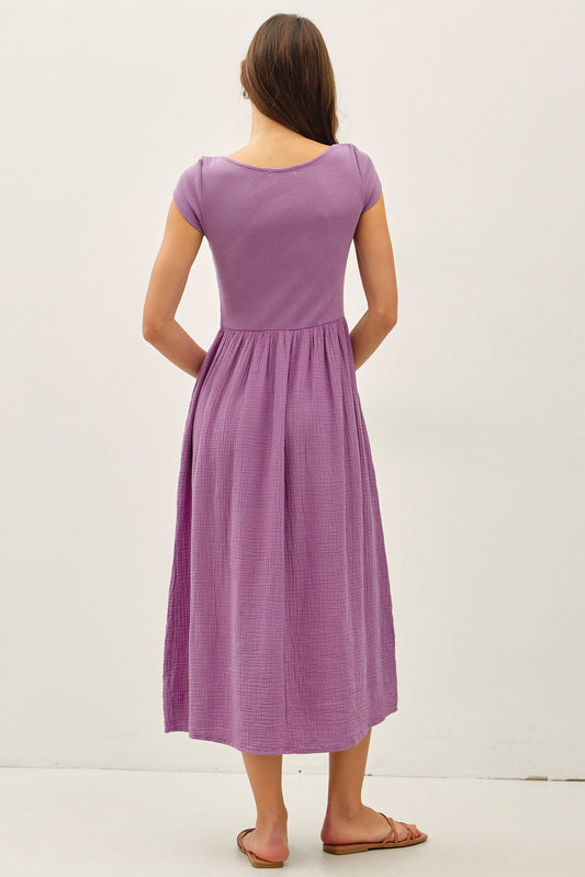 iris purple midi dress featuring a wide boat neckline, short cap sleeves, and a soft gathered waistline with a relaxed flowy skirt.